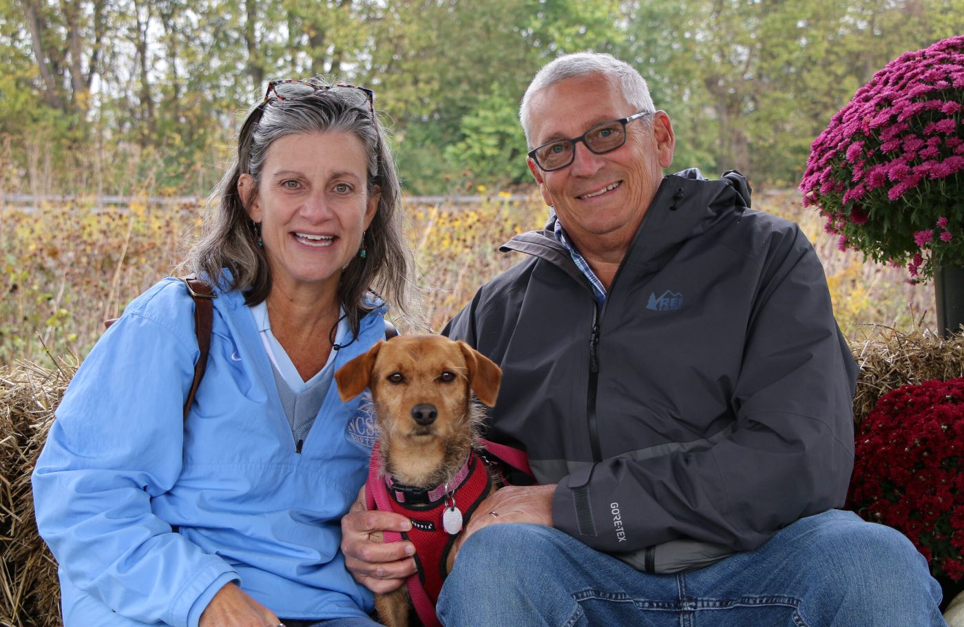 A smiling couple with the small dog they adopted from The National Humane Education Society