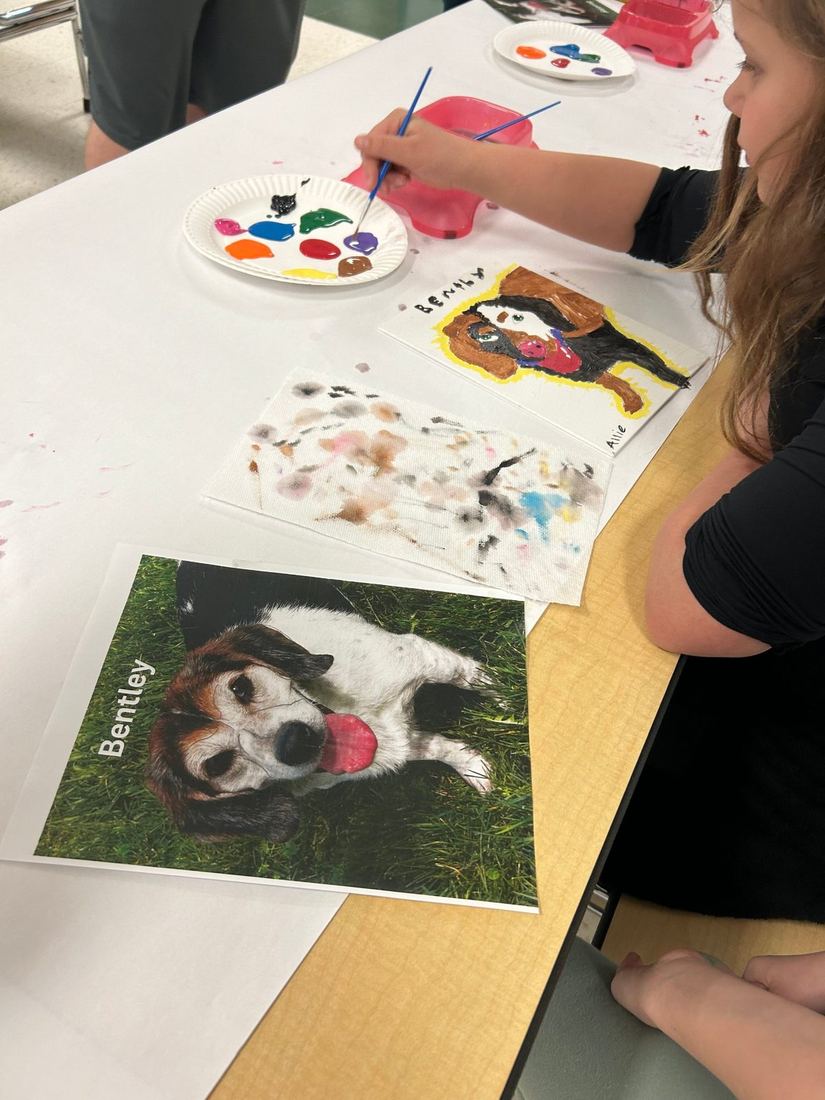 A student painting a portrait of Bentley, an adoptable dog, during an NHES humane education activity