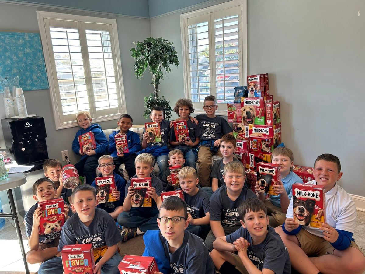 Smiling students holding boxes of dog treats they collected for the animals at NHES